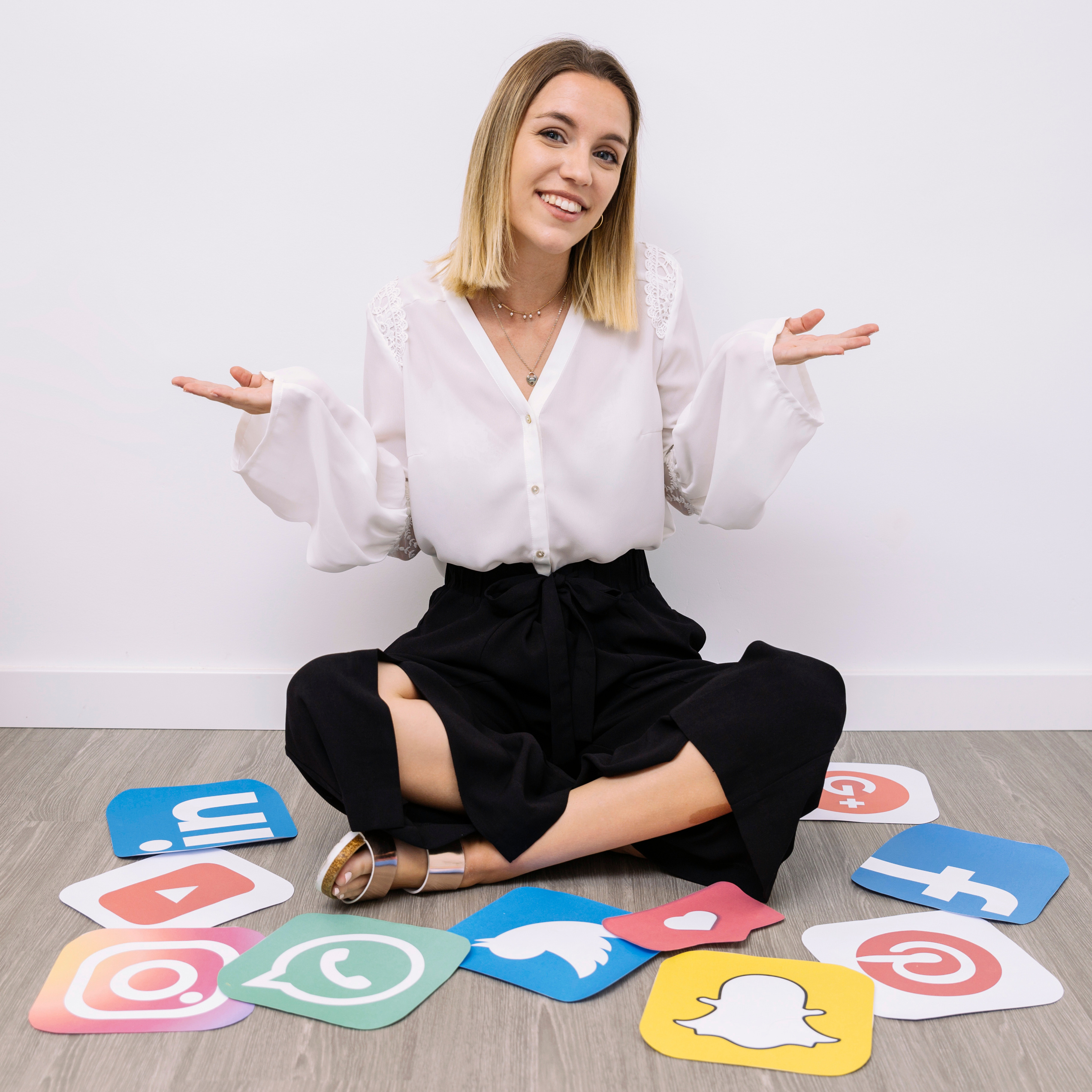 businesswoman sitting floor with social media icons shruggin